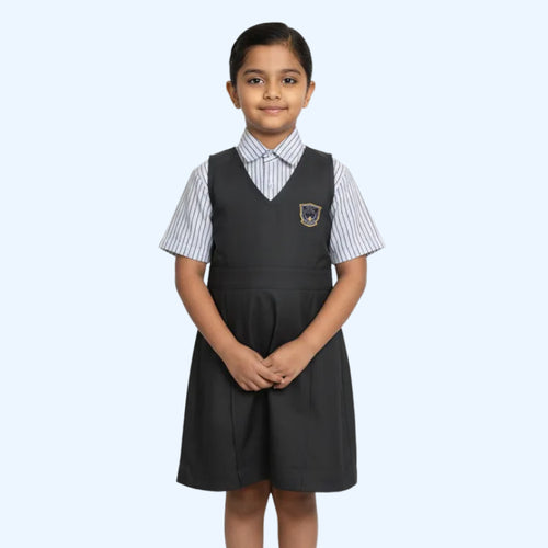 Girl wearing a school uniform with a black pleated skirt and white shirt on a light gray background